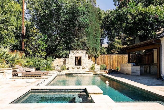 view of swimming pool featuring an in ground hot tub, a patio, and exterior kitchen