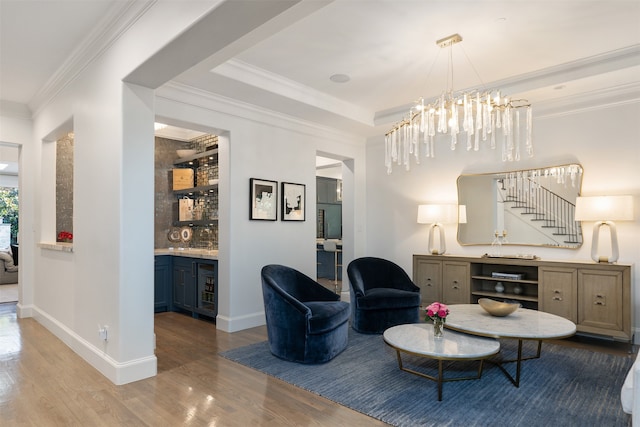 living room with light hardwood / wood-style flooring, an inviting chandelier, beverage cooler, and ornamental molding