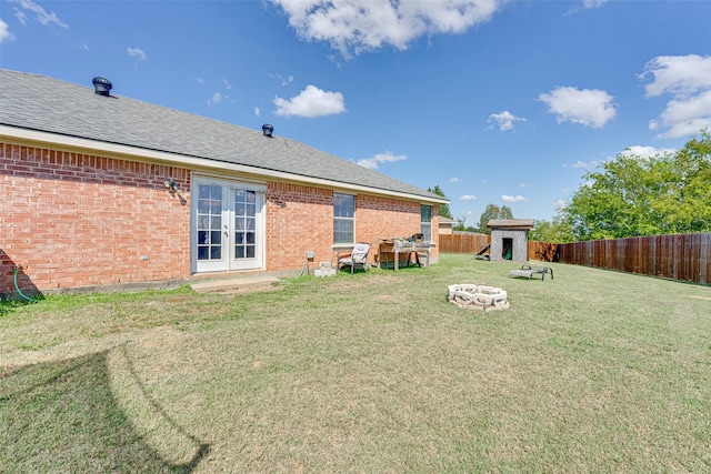 view of yard featuring french doors, a shed, and an outdoor fire pit