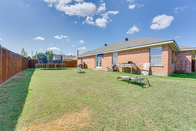 view of yard with a trampoline and a fire pit