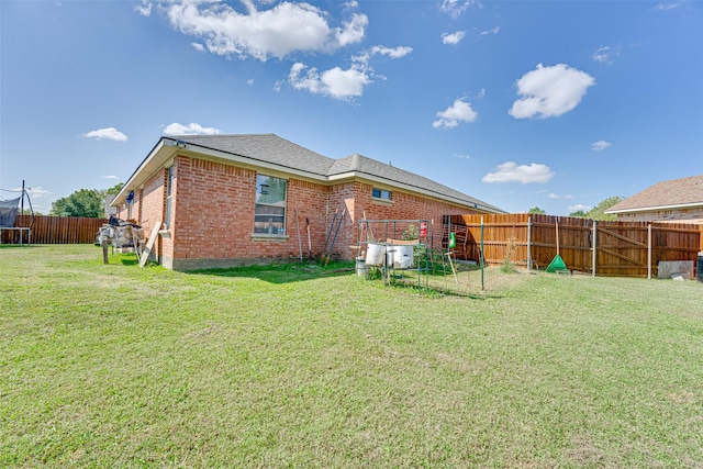 back of property featuring a lawn and a trampoline