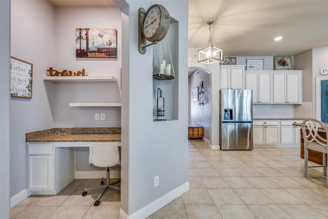 kitchen featuring white cabinetry, stainless steel refrigerator with ice dispenser, backsplash, dark stone countertops, and light tile patterned floors