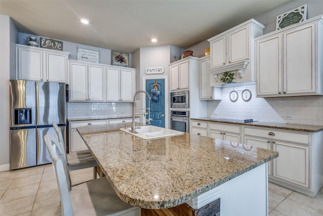 kitchen featuring a breakfast bar area, a kitchen island with sink, sink, and appliances with stainless steel finishes