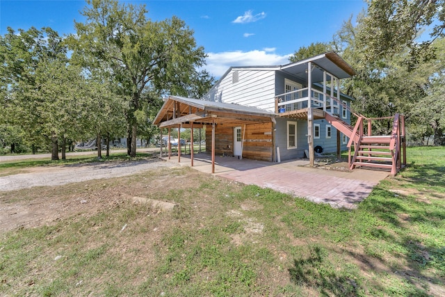 rear view of property featuring a wooden deck, a yard, and a patio area