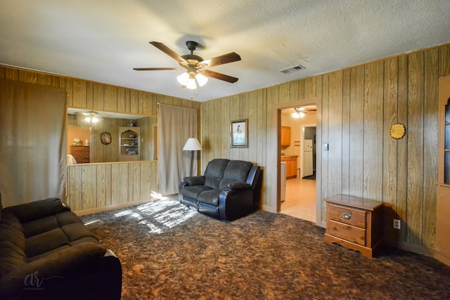 living room featuring wood walls, light carpet, and ceiling fan