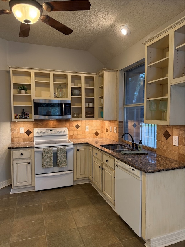 kitchen with sink, dark stone counters, white appliances, and tasteful backsplash