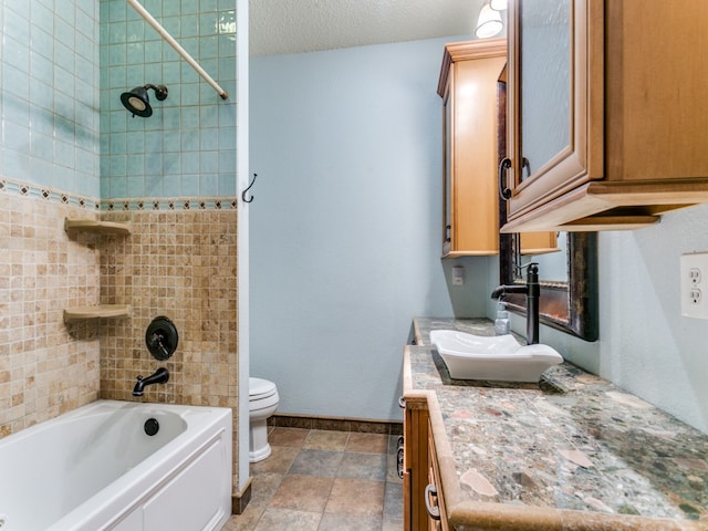 full bathroom featuring toilet, tiled shower / bath combo, vanity, and a textured ceiling