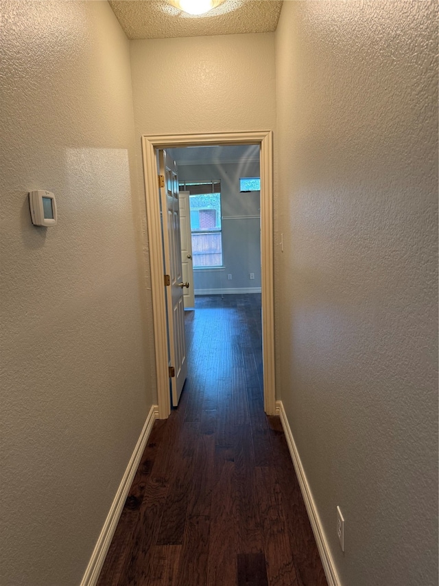 corridor featuring a textured ceiling and dark hardwood / wood-style flooring