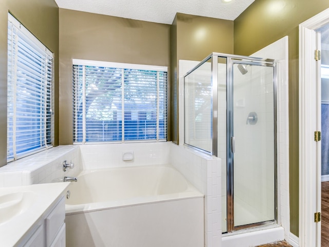 bathroom with vanity, a textured ceiling, hardwood / wood-style flooring, and plus walk in shower