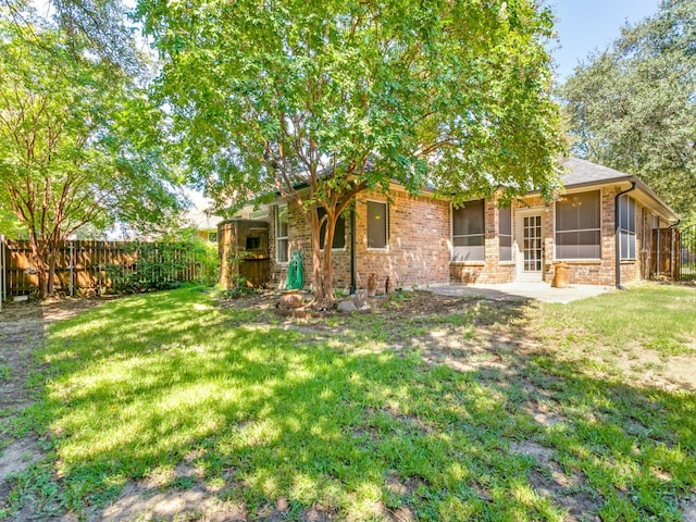 back of house featuring a patio, a lawn, and a sunroom