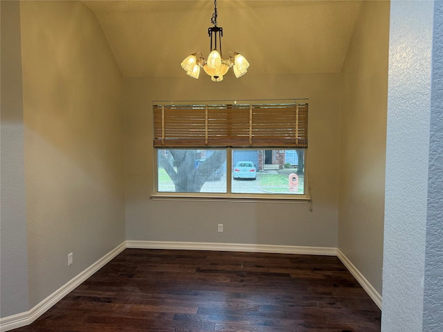 empty room featuring vaulted ceiling, a healthy amount of sunlight, dark hardwood / wood-style flooring, and a chandelier