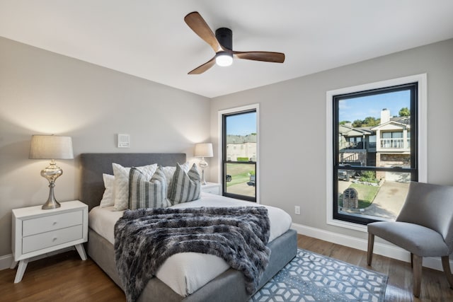 bedroom featuring multiple windows, dark hardwood / wood-style floors, and ceiling fan