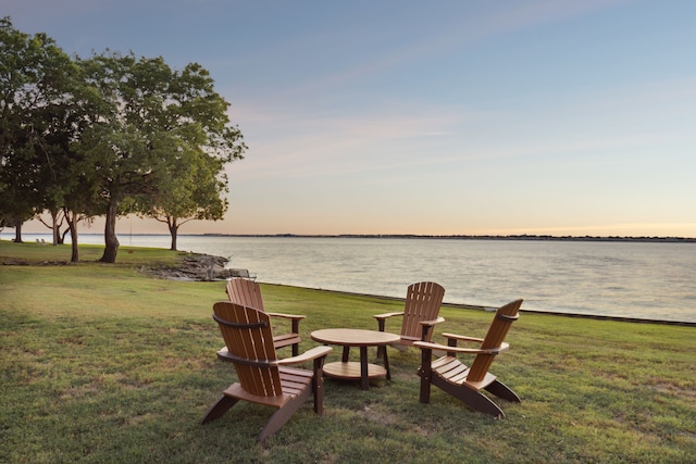 yard at dusk featuring a water view