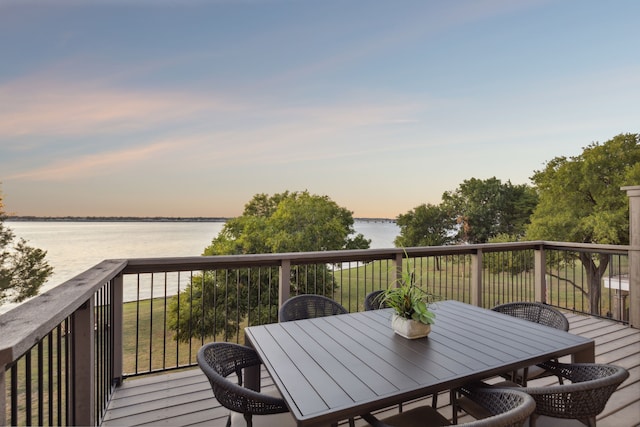 deck at dusk featuring a water view