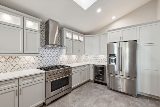 kitchen featuring wine cooler, white cabinets, wall chimney range hood, lofted ceiling with skylight, and high quality appliances