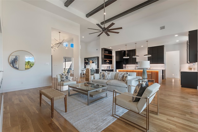 living room with ceiling fan, beamed ceiling, light hardwood / wood-style flooring, and a high ceiling