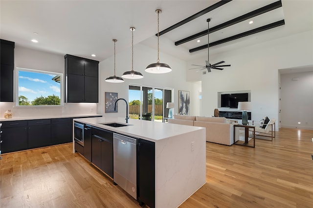 kitchen with light wood-type flooring, a kitchen island with sink, sink, ceiling fan, and stainless steel dishwasher