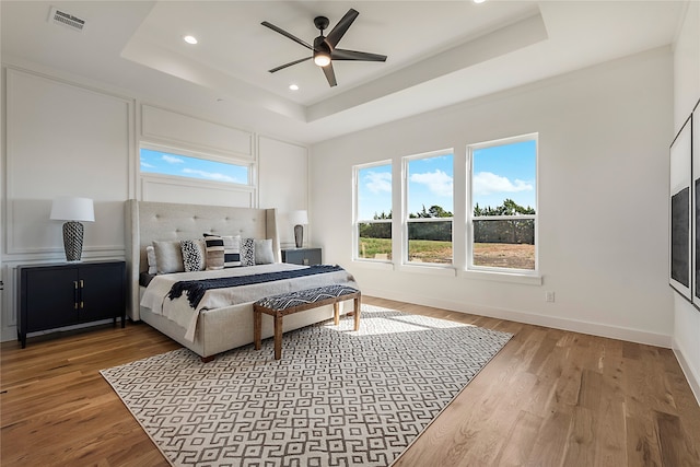 bedroom with a tray ceiling, ceiling fan, and hardwood / wood-style floors