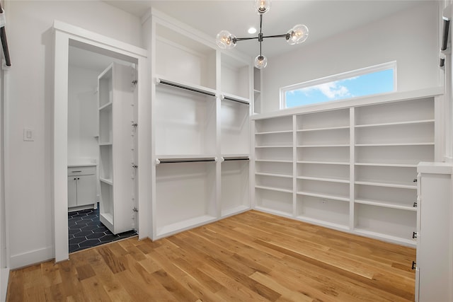 walk in closet with hardwood / wood-style flooring and a chandelier