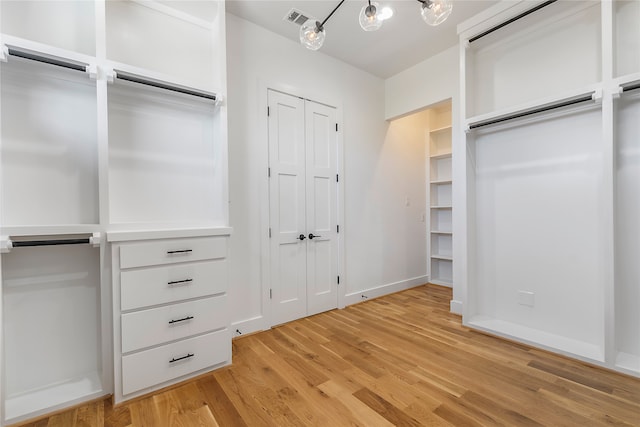 spacious closet with a notable chandelier and light hardwood / wood-style flooring