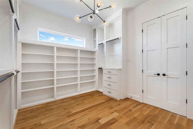 spacious closet featuring a notable chandelier and light hardwood / wood-style floors