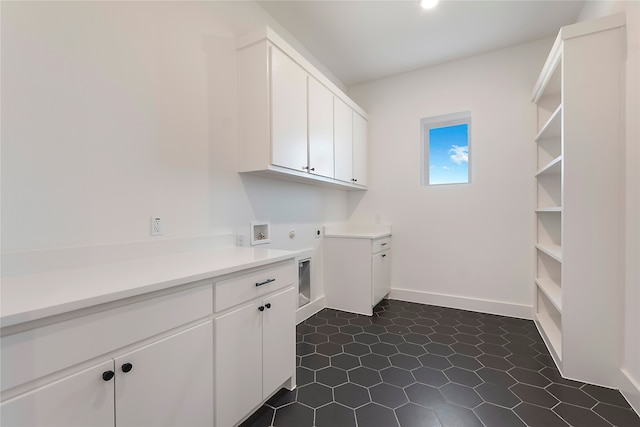 laundry area with cabinets, dark tile patterned flooring, and hookup for a washing machine