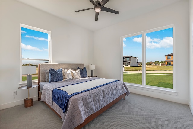 carpeted bedroom featuring multiple windows and ceiling fan