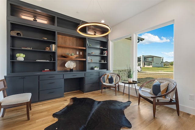 living area with built in desk, light hardwood / wood-style floors, and built in features