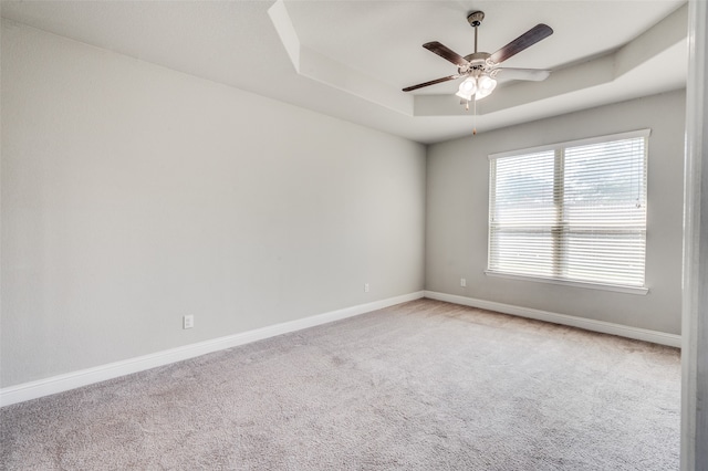 carpeted spare room featuring a tray ceiling and ceiling fan