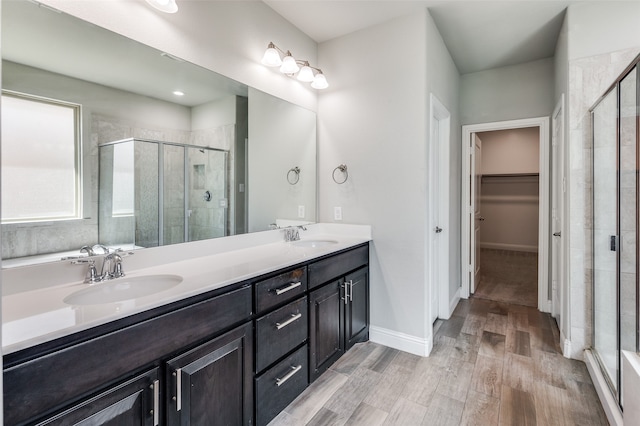 bathroom with hardwood / wood-style flooring, a shower with door, and vanity