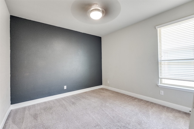 unfurnished room featuring ceiling fan, light colored carpet, and plenty of natural light