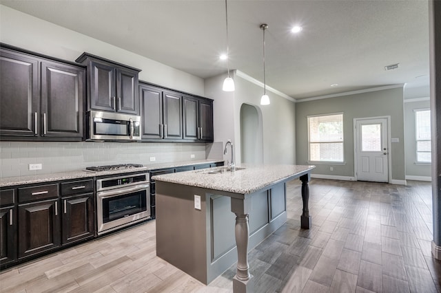 kitchen with pendant lighting, sink, a kitchen bar, a center island with sink, and appliances with stainless steel finishes