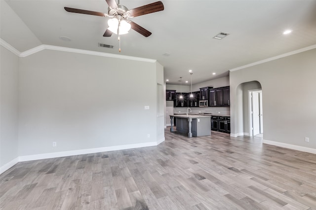 unfurnished living room with ornamental molding, light wood-type flooring, ceiling fan, and sink