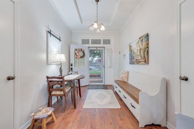 entryway with a raised ceiling, hardwood / wood-style floors, and an inviting chandelier