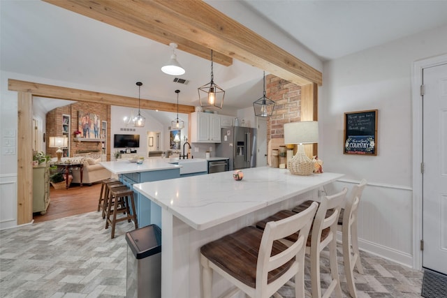 kitchen featuring kitchen peninsula, appliances with stainless steel finishes, a kitchen breakfast bar, vaulted ceiling with beams, and hanging light fixtures