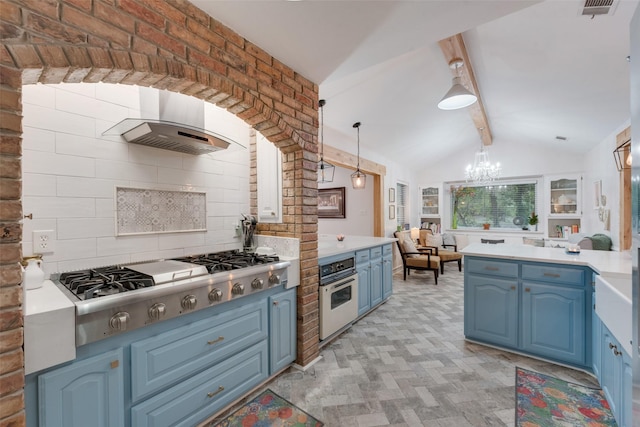 kitchen featuring tasteful backsplash, wall chimney exhaust hood, blue cabinetry, oven, and hanging light fixtures