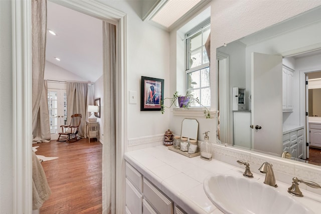 bathroom featuring wood-type flooring, vanity, and lofted ceiling