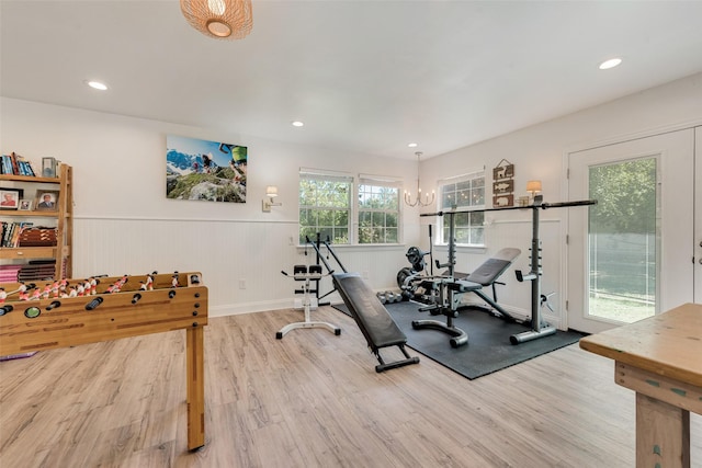 exercise area with hardwood / wood-style flooring and an inviting chandelier