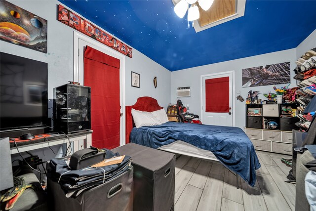 bedroom with ceiling fan, hardwood / wood-style floors, and an AC wall unit