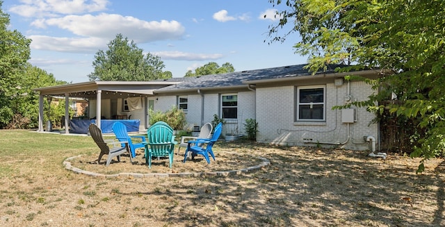 back of house with a fire pit and a lawn