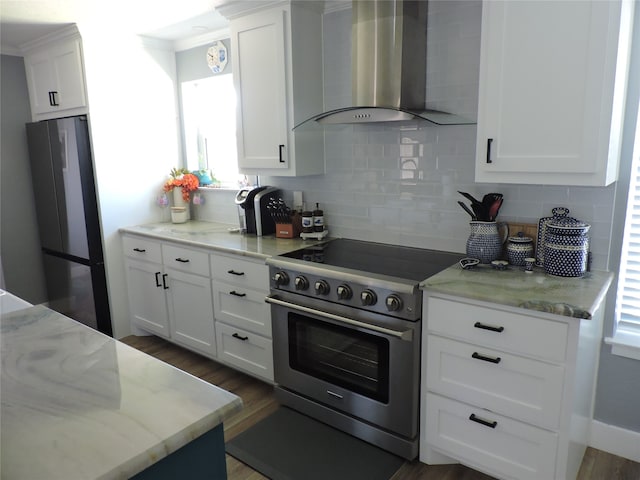 kitchen featuring wall chimney exhaust hood, dark wood-type flooring, backsplash, white cabinets, and appliances with stainless steel finishes