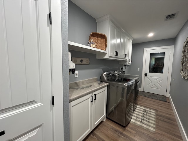 clothes washing area with cabinets, dark hardwood / wood-style floors, and washing machine and clothes dryer