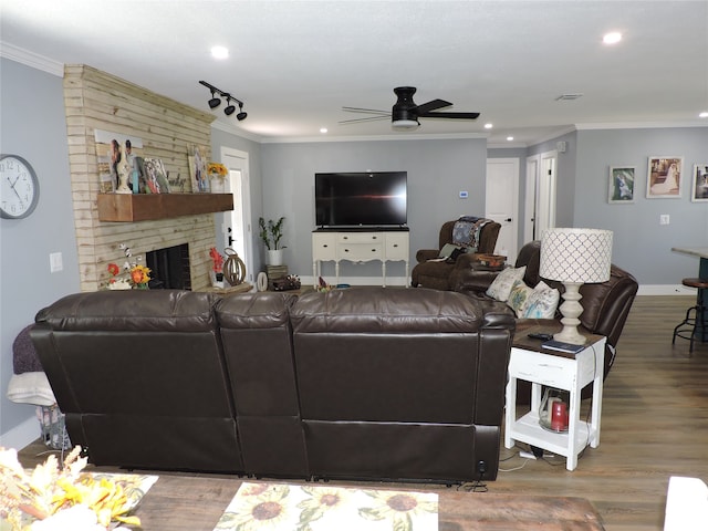 living room featuring ceiling fan, a fireplace, crown molding, and hardwood / wood-style floors