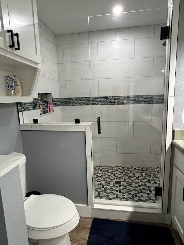 bathroom with an enclosed shower, hardwood / wood-style flooring, vanity, and toilet