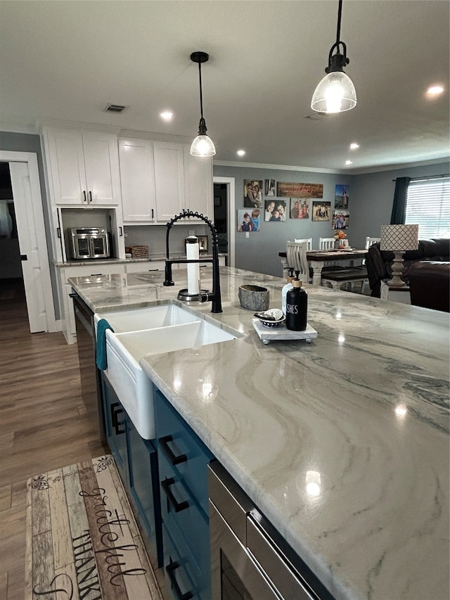 kitchen featuring white cabinets, light stone countertops, hanging light fixtures, and dark hardwood / wood-style flooring