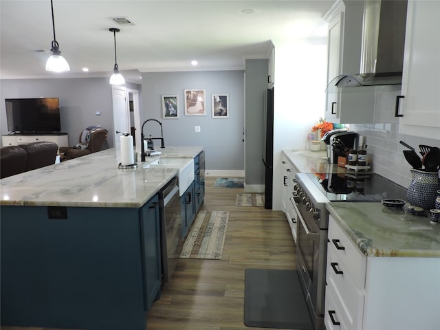 kitchen featuring wall chimney range hood, hanging light fixtures, stainless steel appliances, and white cabinets