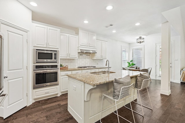 kitchen with stainless steel appliances, white cabinetry, a center island with sink, and sink