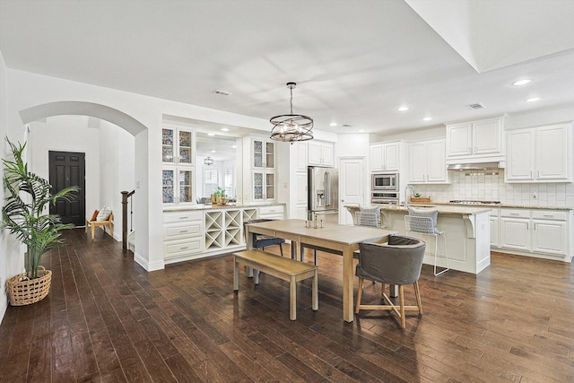 dining space featuring visible vents, arched walkways, dark wood-type flooring, and recessed lighting