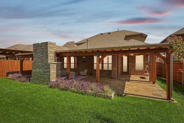 back house at dusk with a yard and a patio area