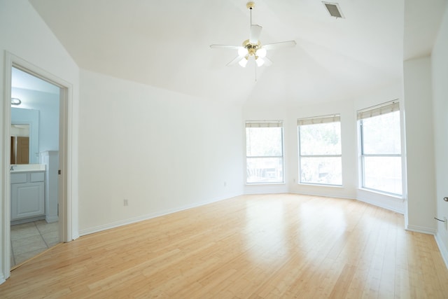 empty room with lofted ceiling, light hardwood / wood-style floors, ceiling fan, and a healthy amount of sunlight